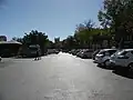 Ici se trouve désormais la route traversant la place dans sa longueur. Les enfants avaient l'habitude de courir, de jouer au foot et de faire des tours de vélo sur cette partie de la place, mais cela se faisait entre les voitures qui venaient se garer.