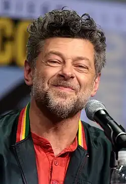 Photographie d'un homme souriant derrière un micro.
