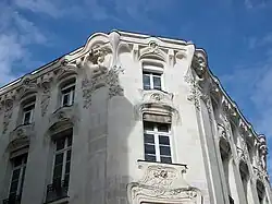  Photographie du haut d'une façade d'immeuble décoré de bustes de femmes.