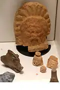 Antéfixe à tête de silène, devant lui à gauchetête de sanglier et à droitepetit vase à parfum en forme de tête de gorgone.