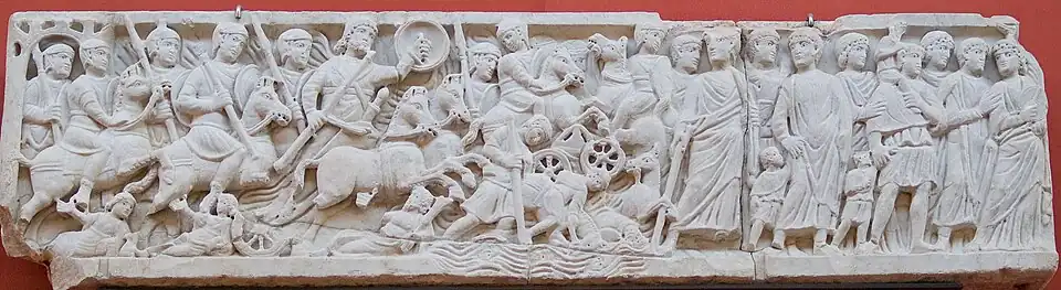 Sculpture montrant des hommes et des bêtes qui semblent se tenir sur un cours d'eau. À la droite, des hommes se trouvent sur une berge.