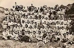 Photo de groupe de militaires, la majorité en tenue de service en toile claire, certains en uniforme kaki ou bleu horizon. Deux mulets participent à la photo, cachés parmi les soldats.