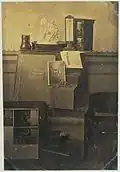Nature morte avec des photographies dans un cadre, un album photo, une lentille, un moulâge en plâtre d'Ariadne, un thermomètre et une copie de la Revue Photographique, vers 1855