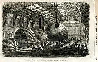 Dessin en noir et blanc de ballons assemblés sous la verrière d'une gare.