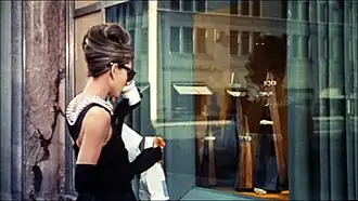 Audrey Hepburn, en tenu de soirée, buvant un café à emporter et avec un croissant à la main, devant la vitrine du joaillier Tiffany à New York