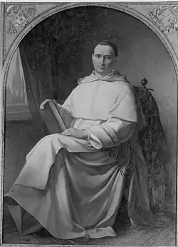 Un curé, le Père Jean Baptiste Henri Lacordaire, pose, dans ses habits ecclésiastiques, assis et tenant un livre à la main.