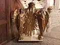 Deux anges soulèvent une couronne devant un panneau rayonnant