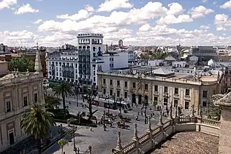 L'avenue de la Constitution vue depuis la cathédrale avec, tout à gauche, une partie des Archives générales des Indes. De l'autre côté de l'avenue se trouvent, à gauche, le bâtiment blanc de la compagnie d'assurances La Aurora (construit entre 1933 et 1936 par Antonio Illanes) et, à gauche, le bâtiment de la poste, de style néo-baroque, construit entre 1927 et 1930.