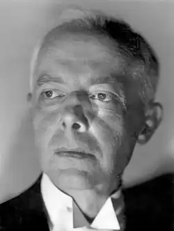 Le visage de Béla Bartók photographié dans les années 1940. Il est un peu ridé, ses cheveux blancs se font rares. La photo est en noir et blanc, Bartók est très légèrement tourné vers la gauche, son regard est dans le vide, vers la gauche de l'image. Le fond est uni, clair, la source lumineuse est sous le visage.