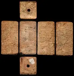 Quatre vues d'un pavé en argile présentant sur chaque face des inscriptions.