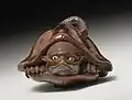 Netsuke représentant tanuki sous une large feuille de lotus, début du XIXème siècle.