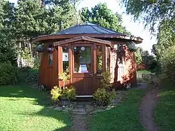 Photographie d'une maison circulaire fabriquée en bois et surmontée d'un toit en pente.
