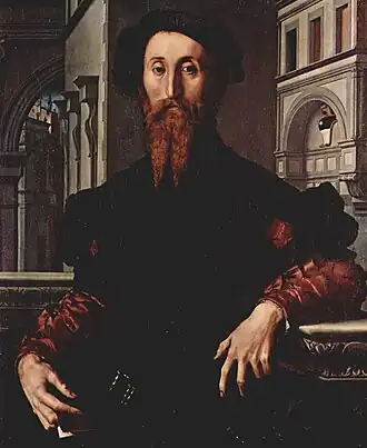 Tableau montrant un homme roux et barbu, debout et regardant le peintre, devant un décor urbain dense de style Renaissance.