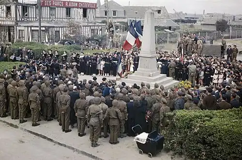 La cérémonie officielle au monument aux morts de Courseulles-sur-Mer le 14 juillet 1944, jour de la fête nationale, en présence de la population locale et de militaires de l'Armée française de la Libération et d'unités alliées.