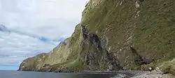 Falaise imposante de l'île avec une petite plage à son pied