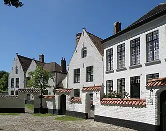 Maisons no&nbsp;16 (à droite, millésimé 1854 en façade), no&nbsp;18 (au centre, XVIe et XVIIe&nbsp;siècles) et no&nbsp;20 (double pignon de gauche, également des XVIe et XVIIe). Le mur de séparation entre jardinets des maisons et enclos central est bien visible.