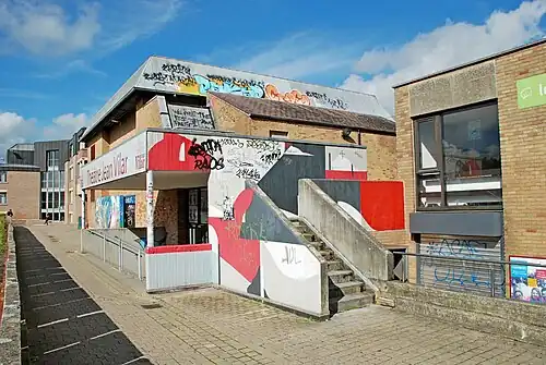 Le porche d'entrée en béton situé au sud, orné de peintures murales de Fredone Fone.
