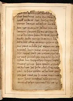 Photo de la page de droite d'un livre ouvert. À l'intérieur d'un cadre blanc, on peut voir une feuille de vélin couverte de texte à l'encre noir dont les bords en haut et à droite sont très irréguliers.