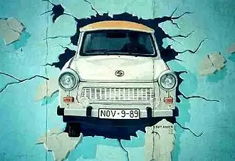 Une Trabant passant le mur de Berlin.