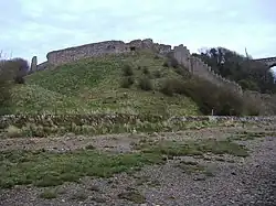 Un mur de pierre en ruine sur un monticule herbeux