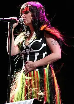 Image d'une chanteuse brune portant une robe composée d'un haut en forme de squelette et d'une jupe de plusieurs couleurs