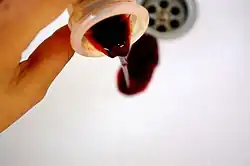 Une coupe menstruelle contenant du sang est vidée dans un lavabo