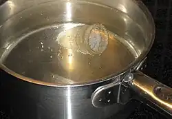 Une coupe menstruelle transparente plongée dans une casserole d'eau bouillante.