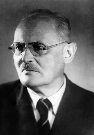 Photo en noir et blanc d'un homme à lunettes rondes.