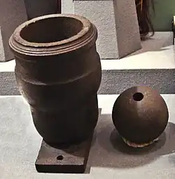 Photographie d'un mortier et d'un obus de mortier à l'aspect vieilli dans un musée.