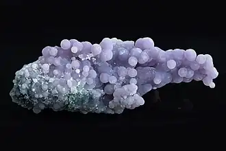 Assemblage de petites sphères de pierres mattes formant une grappe agglomérée à un fond bleu granuleux.