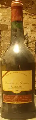 La photo couleur représente une bouteille couverte de poussière révélant don vieillissement.