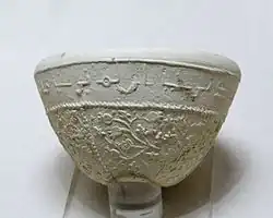 Photographie d'un bol à décor de pampres et de grenades avec inscription en arabe, céramique argileuse à décor moulé de Suse des VIIe – VIIIe siècles, musée du Louvre