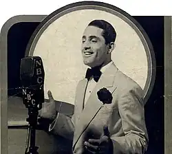 Un homme caucasien des années 1930 devant un micro.
