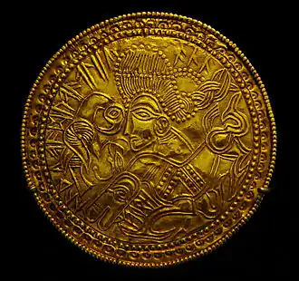 Bractéate avec un visage et l'inscription runique « Le Très Haut », un nom d'Odin.