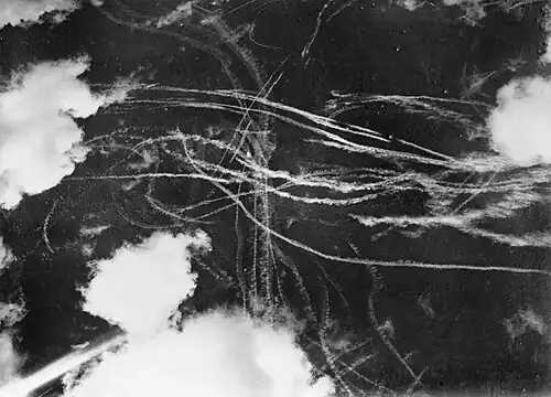 Image du ciel avec des nuages et plusieurs traînées de condensation provoquées par des avions. Chaque courbe autour d'une autre indique un combat aérien