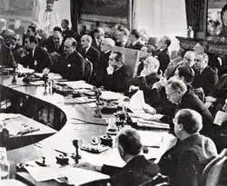 Photographie d'une table ronde autour de laquelle sont assis de nombreux hommes en costume.