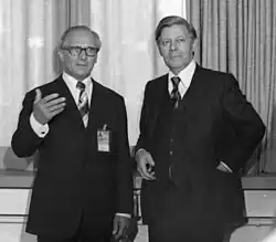 Photo noir et blanc de deux hommes debout en costume sombre.