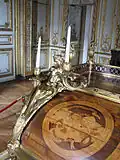 Bronze masculin et détail de la partie gauche de l'abattant avec une marqueterie illustrant la Poésie dramatique reprenant la mention latine NON NISI GRANDIA CANTO  — IRRINDENS CUSPIDE FIGO,  tirés de l'Iconologia de Cesare Ripa (« Je ne chante rien que des choses assez grandes - Moqueuse, je transperce de ma lance »).