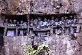 Site funéraire toraja en Indonésie : balcon creusé dans la falaise avec exposition de poupées à l'effigie des défunts.
