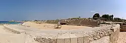 Photographie d'un amphithéâtre en ruine au bord de la mer.