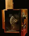 Cinématographe vu de face (couvercle objectif ouvert). On voit l'obturateur mobile à disque et la fenêtre de cadrage du film.