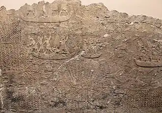 Combats dans les marécages : des soldats assyriens, sur des bateaux, débusquent des fuyards des ennemis vaincus, certains essayant de se cacher au milieu des roseaux.