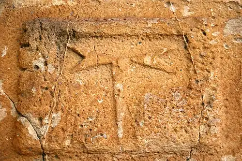 Le tau sculpté à la base du clocher.