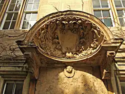 un grand coquillage avec un bouclier au centre et des feuilles sculptées autour ; une tête de chérubin sous le coquillage