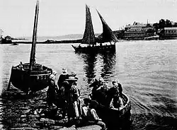Douarnenez : canots transportant les ouvrières aux friteries qu'on aperçoit à l'arrière-plan (Le Mois littéraire et pittoresque, 1902).