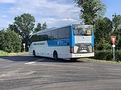Un autocar blanc et bleue partant en direction de la gauche de l'image.