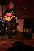 Photo montrant un homme de face tenant une guitare basse.