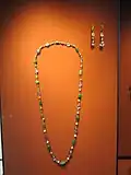 Un des colliers (fait de perles et de saphirs) à côté de la paire de boucles d'oreille.