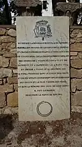 Pierre tombale en français avec une inscription et un blason dans la partie supérieure.