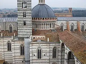 Mélange d'architecture romane (dôme et campanile) et gothique (murs et baies) en marbre blanc et noir, du XIIe au XIVe&nbsp;siècle, de la cathédrale de Sienne.